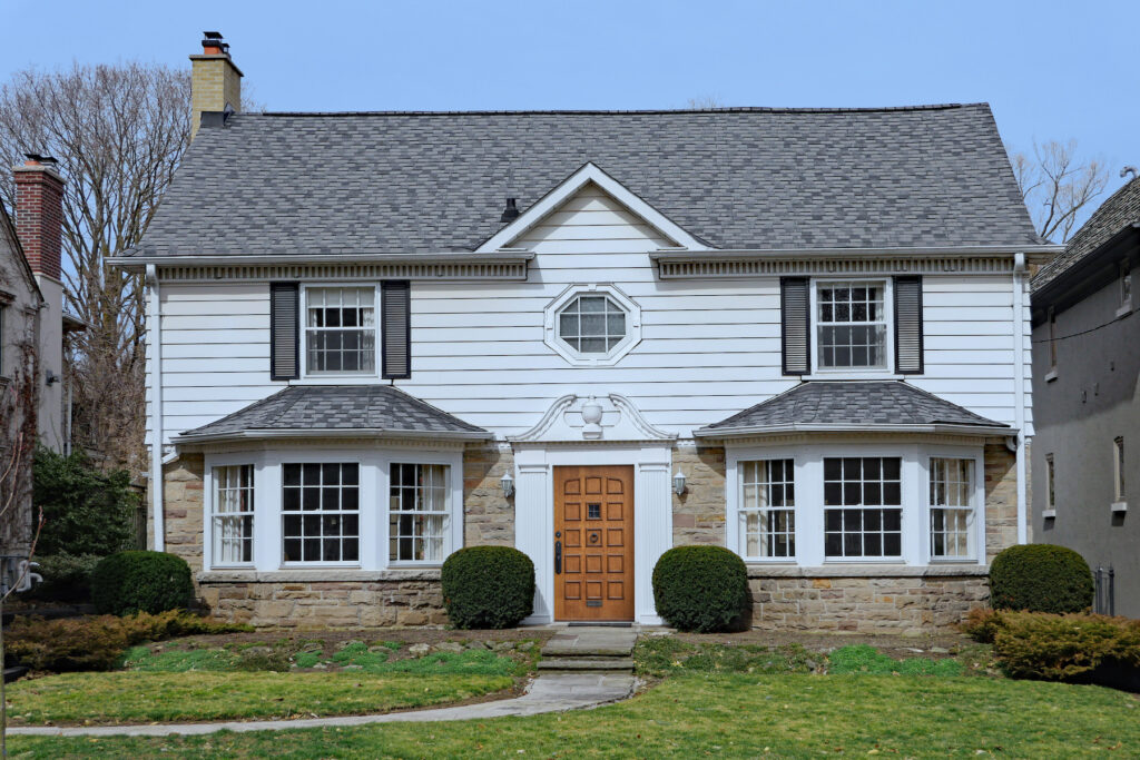 white house with 2 bay windows and a bright oak door