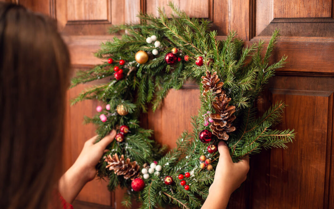 a woman placing a wreath on a door using a hook