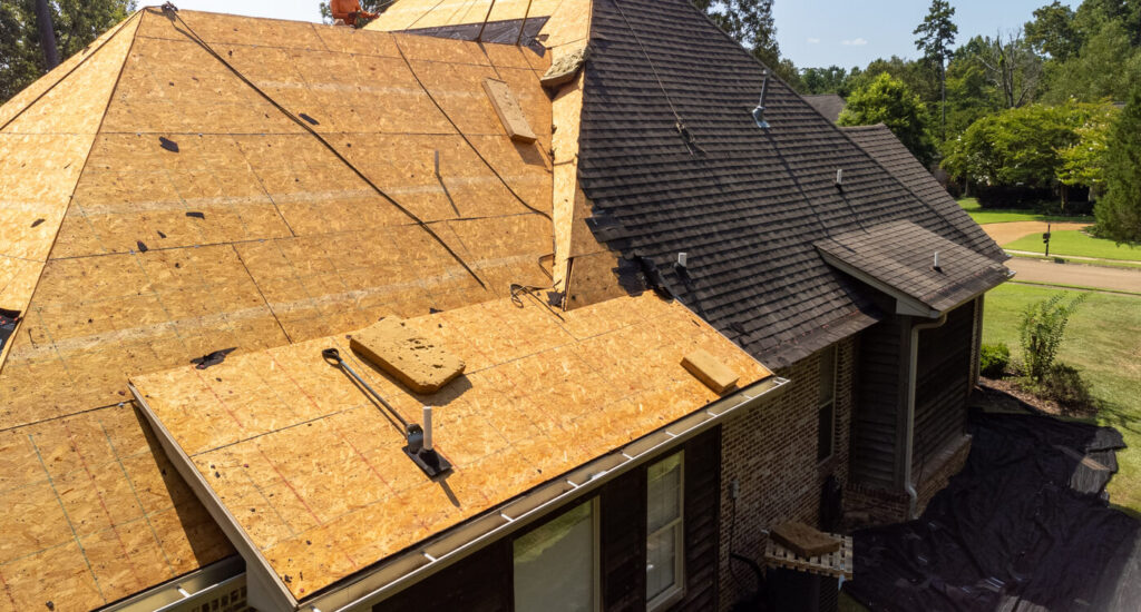 A modern home with roof repair being done and exposed plywood.